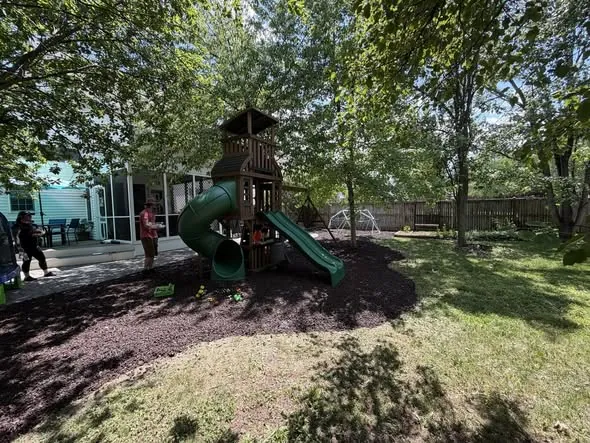 Assembled backyard playset on a fresh mulch bed